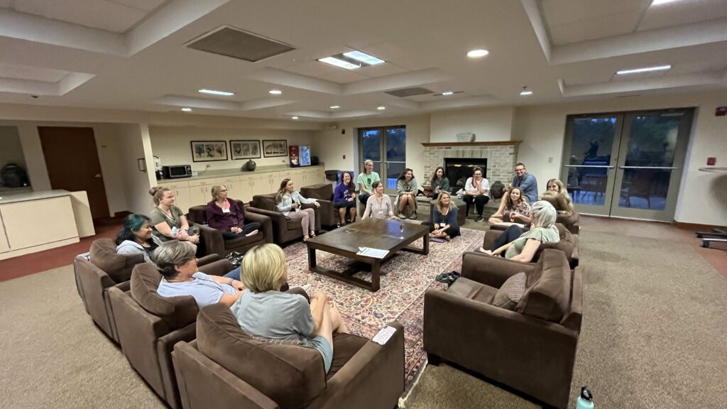 therapists sitting in overside chairs in a circle getting to know each other during a welcome session at the Grounded to Grow retreat