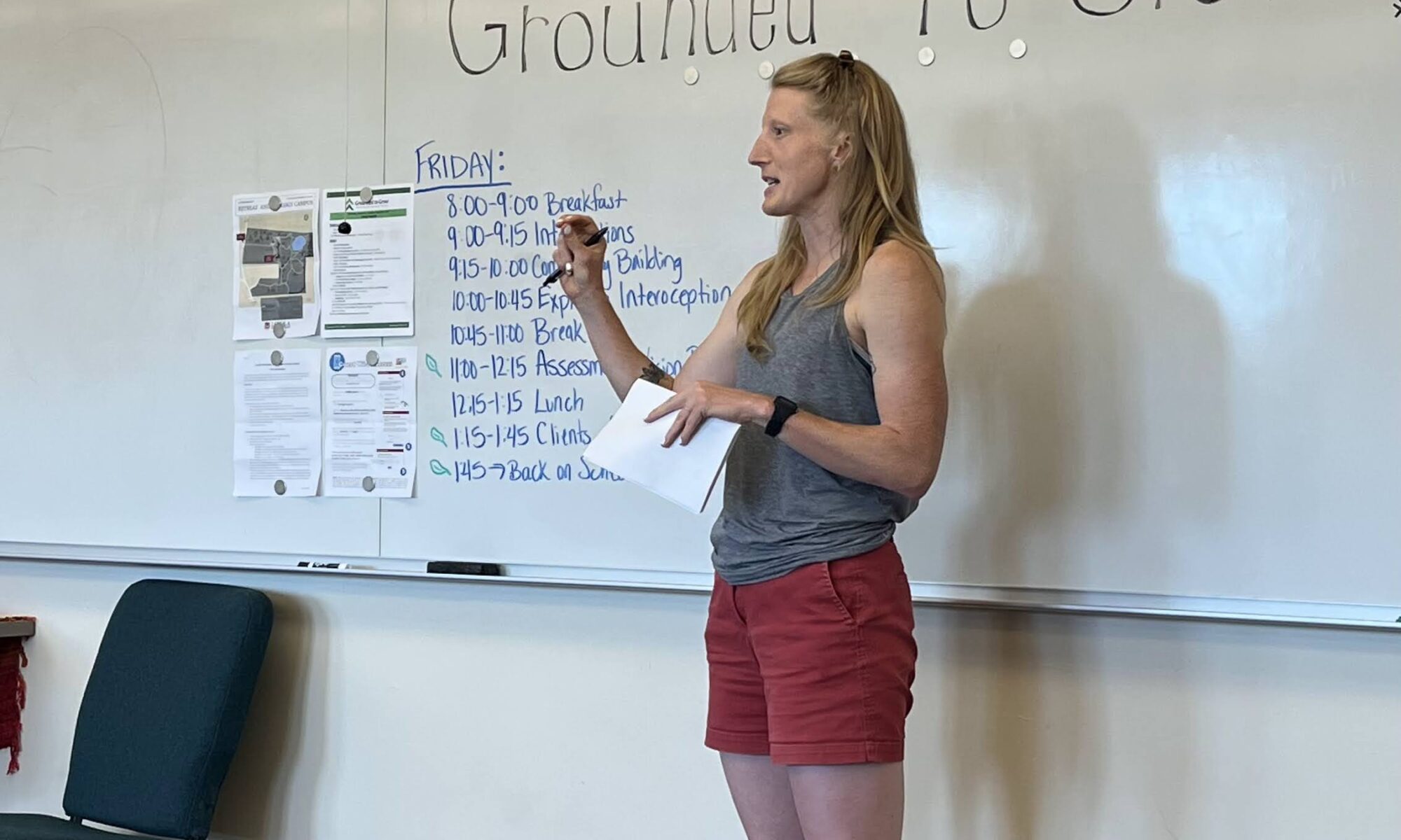 a retreat coordinator reviewing the daily agenda in front of a white board at the nature based therapy retreat